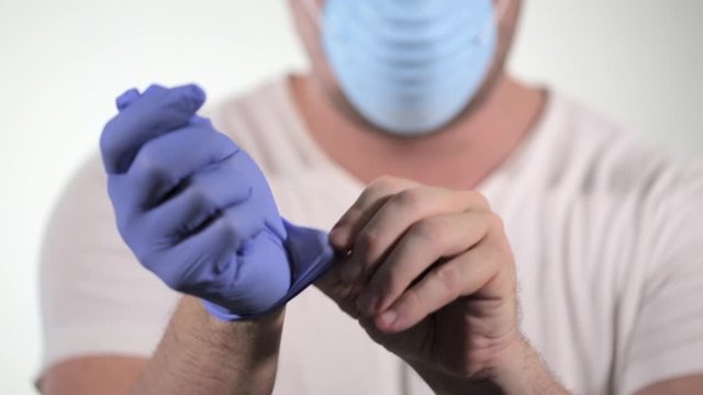man removing blue medical safety latex gloves during coronavirus COVID-19 pandemic