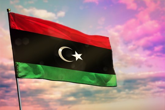 Fluttering Libya flag on colorful cloudy sky background. Prosperity concept.