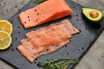 Fresh sliced salmon fillet with arugula, avocado and lemon on slate plate. Wild atlantic fish