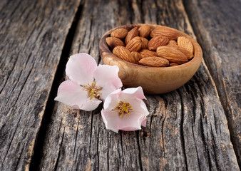 Almond nuts with flowers in closeup isolated on wooden background.