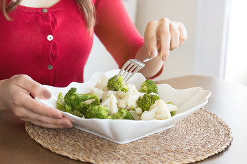 Girl eating delicious cauliflower and broccoli salad. Diet salad