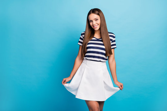 Photo of pretty charming lady traveler hold short wavy skirt good mood long hairstyle toothy smiling wear white striped sun mini summer dress isolated blue background