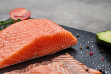 Fresh sliced salmon fillet with arugula, avocado and lemon on slate plate. Wild atlantic fish