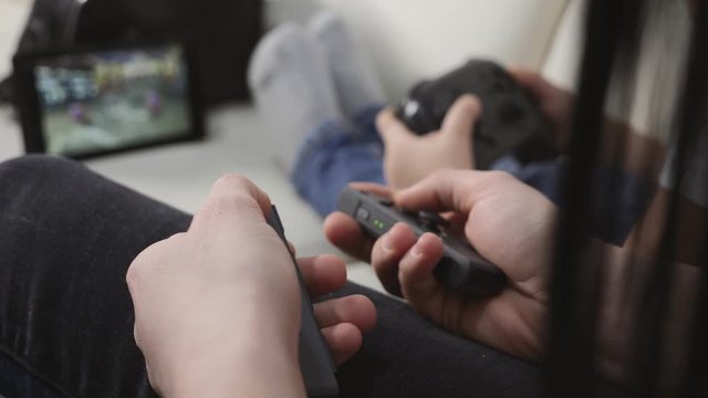 Children play video games, top view, close-up holding a joystick and pressing buttons.