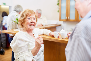 Fröhliche Seniorin im Altersheim redet und flirtet mit Senior im Gemeinschaftsraum