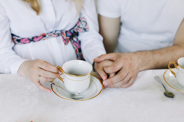 Fototapeta na wymiar Hands of happy couple drinking hot tea at home. Happy family lunch concept. hands of lovers drinking tea. breakfast at home 