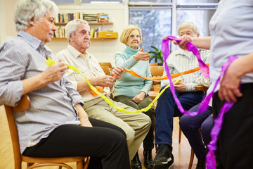 Senioren mit Demenz machen eine Übung mit bunten Stoffbändern für Interaktion