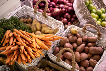 Assortimento di carote, cipolle rosse lime ben esposti in delle ceste al mercato