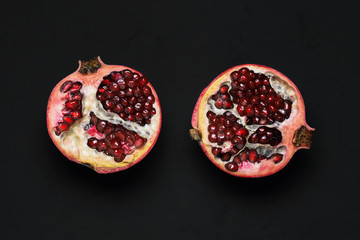 Two halves of a ripe pomegranate on a black background. Fresh red pomegranate with grains. The view from the top.