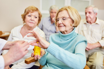 Obraz na płótnie Canvas Arzt verteilt Tabletten an eine alte Frau im Gesundheitskurs im Seniorenheim