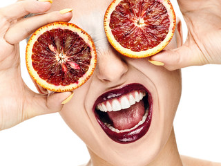 a cheerful girl with a beautiful smile and red oranges in her eyes