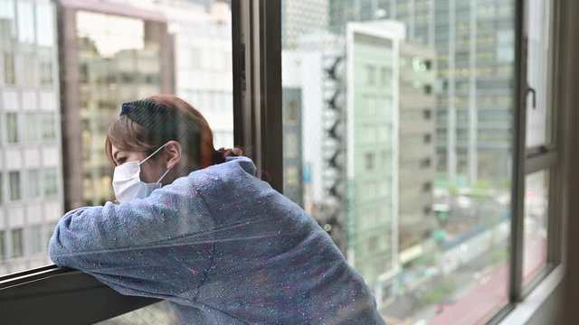 寂しそうに外を眺める、コロナウイルスで外出自粛をする女性