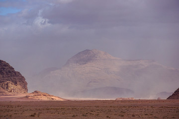 Fototapeta na wymiar WADI RUM DESERT, JORDAN - FEBRUARY 08, 2020: Iluminated rock massifs emerging from a sand storm