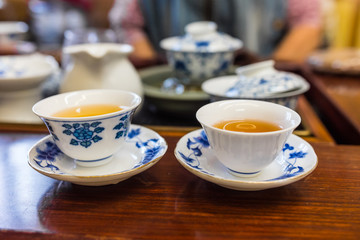 Porcelain tea cups with beautiful blue patterns. Filled with Pu Erh tea, gung fu cha style. Blurred background. 