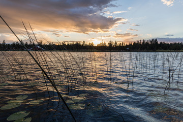 sunset on a lake during a day with clouds, the water shows small waves due to the wind