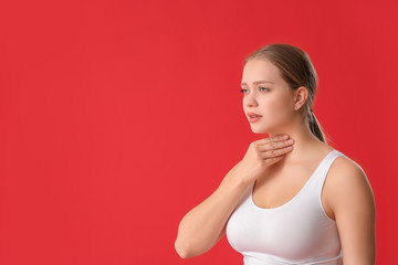 Young woman with thyroid gland problem on color background
