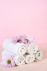 Fototapeta na wymiar Set of towels with flowers for Spa treatments on a pink background. Copy space