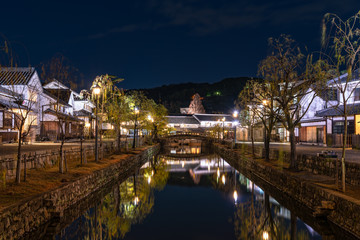 Fototapeta na wymiar Kurashiki Bikan Historical Quarter light up at night. Townscape known for characteristically Japanese white wall of residence and willow tree lining banks of Kurashiki River. Okayama Prefecture, Japan