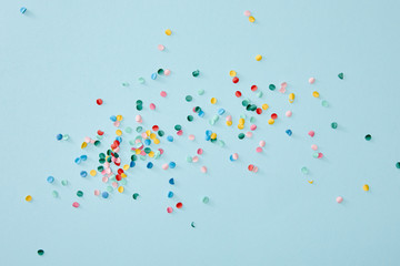 Top view of colorful confetti scattered on blue background
