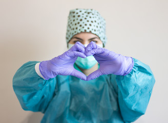 Photo of nurse making heart sign with her hands. Focused hands.