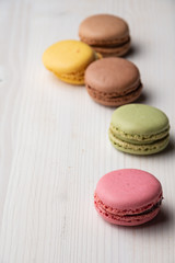Top view of colored macarons, with selective focus, on white wooden table, vertical, with copy space