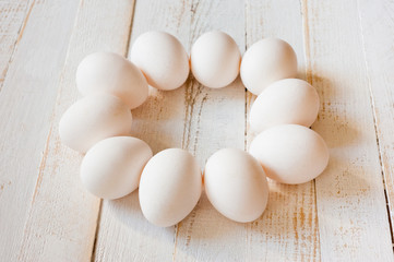 White chicken eggs lying on a white painted wooden surface. Background for livestock products.