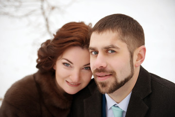 Loving couple smiling in a winter park close-up.