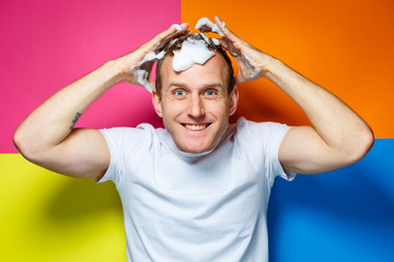 Portrait of a young, handsome, cheerful guy on a multi-colored background, dressed in a white...