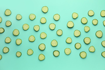 Green cut cucumbers on color background