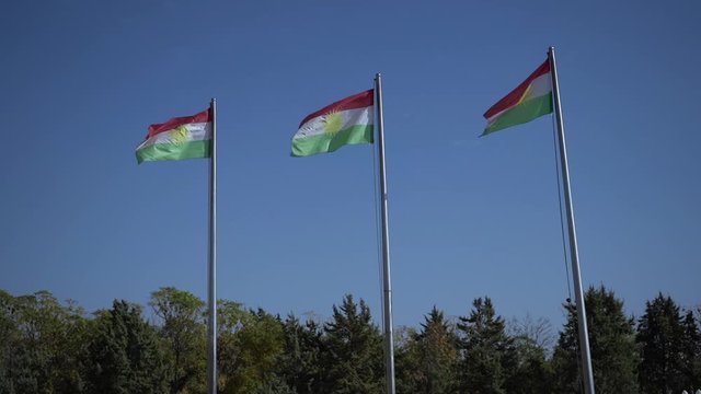 Three Kurdish National Flags in Row Waving on Wind in Public Park. Erbil, Kurdistan, Iraq