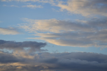 Low gray clouds in the day sky, illuminated by the rays of the sun