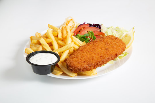 Horizontal image consisting of fried fish, french fries, vegetable and garlic sauce on the plate with white background. 
