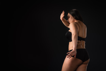 Plus size girl hiding her body and showing stop gesture isolated on black