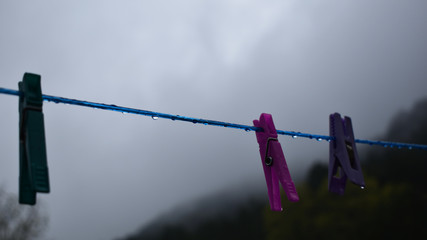Fototapeta na wymiar Wäscheklammer an nasser Wäscheleine im Regen, grauer Himmel