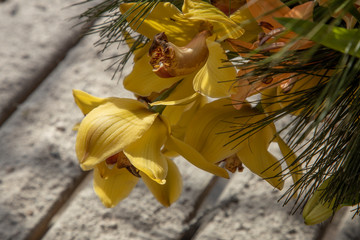 Yellow orchid in a flower arrangement on a wooden table