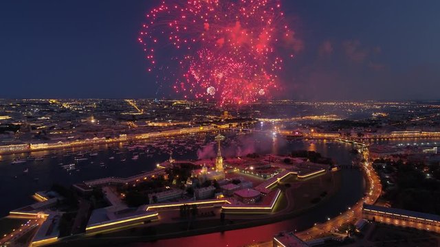 Beautiful festive salute firework St. Petersburg over Peter and Paul epic fortress huge sparks. Night downtown historical cityscape. Neva river reflection. Ships. Russian Navy Day Aerial forward