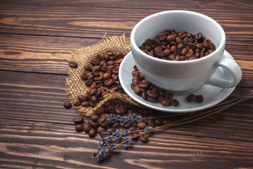 Cup with black coffee, coffee beans and sprigs of lavender on a wooden tabletop