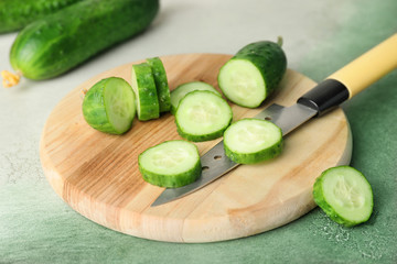 Green cucumbers, cutting board and knife on table