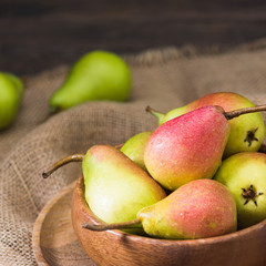 Pears in a wooden bowl on a brown wooden table. Seasonal fruits	