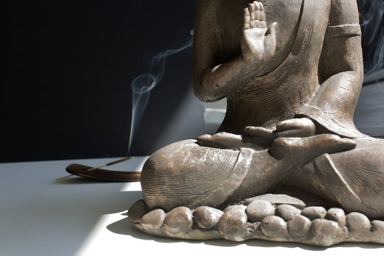 Close up Buddha statue detail with insence stck into sun light hope pray meditation calm down concept 