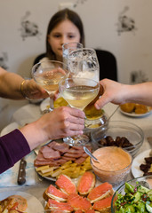 Obraz na płótnie Canvas Friends and family people hands toasting white wine at the festive table