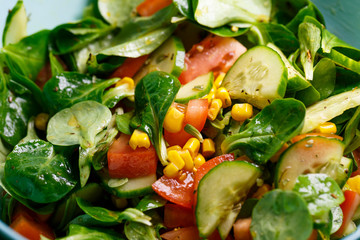 Spinach, corn, tomato and cucumber salad with olive oil. Food is proper nutrition. Vegetarian food
