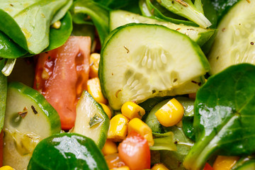 Spinach, corn, tomato and cucumber salad with olive oil. Food is proper nutrition. Vegetarian food