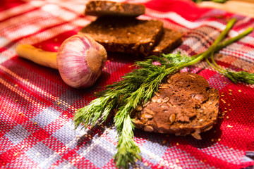 Gray bread on a tablecloth with dill, garlic, wooden table
