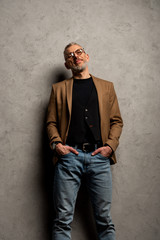Fototapeta premium handsome businessman in glasses standing with hands in pockets on grey