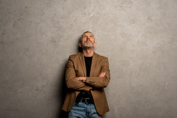 businessman in blazer standing with crossed arms on grey