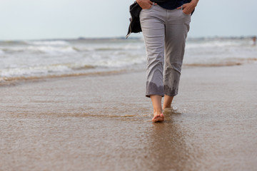 Female feet are walking along the beach