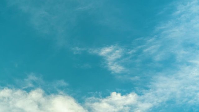 Timelapse of fluffy clouds gliding by below the heavenly blue sky, low angle 4K