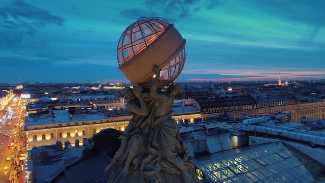 Aerial close up women holding a glass globe Singer historic building dome book house on st. Petersburg Nevsky prospect monument. Road traffic. Night backlight cityscape. Festive fireworks. Roof. Drone