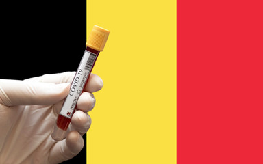COVID-19 Pandemic Coronavirus concept ; Close-up of a Positive COVID-19 blood test sample tube with Flag of Belgium at background. Blood testing for diagnosis new Corona virus infection.
